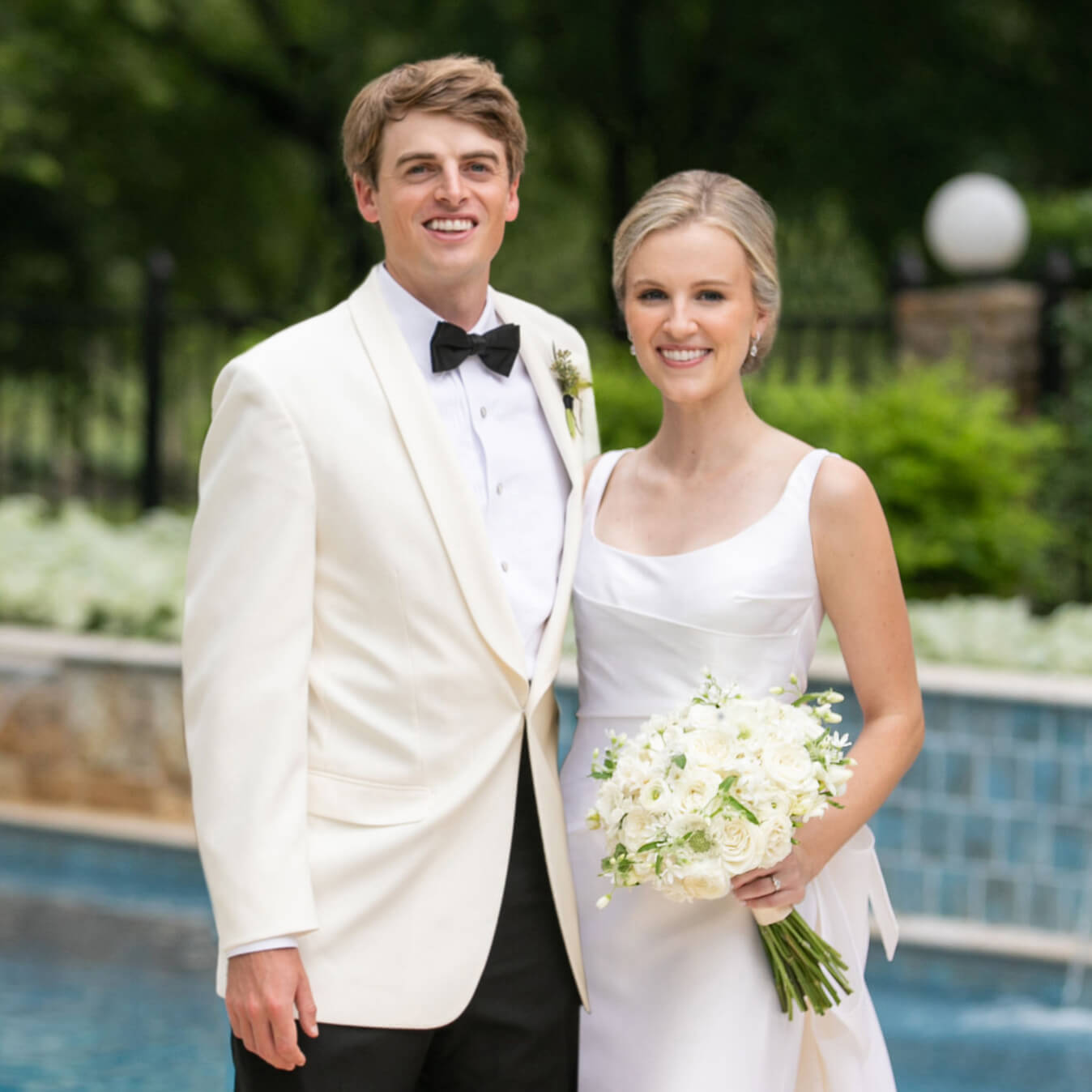 Bride and groom in white posing together outdoors