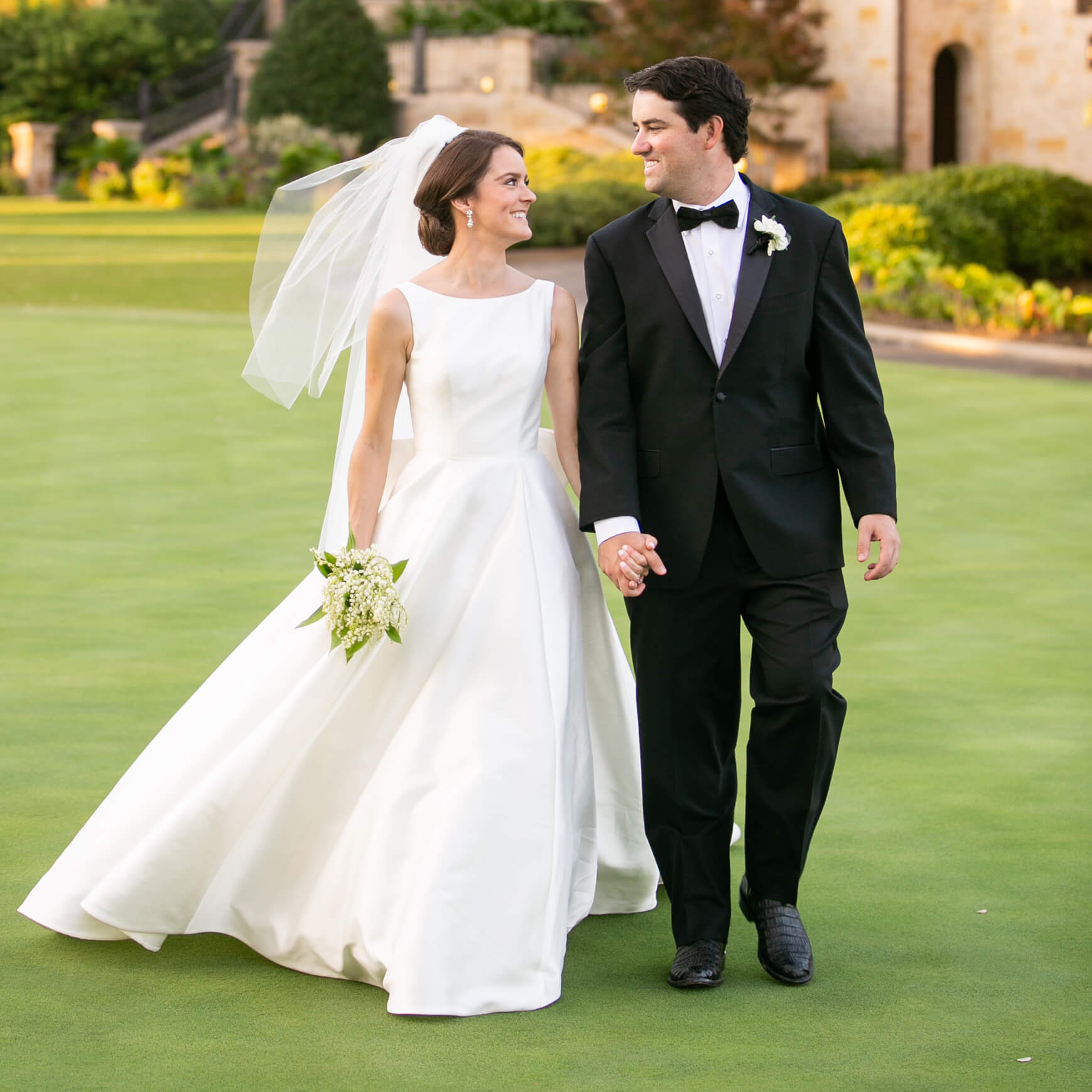 Bride and groom walking in grass hand and hand