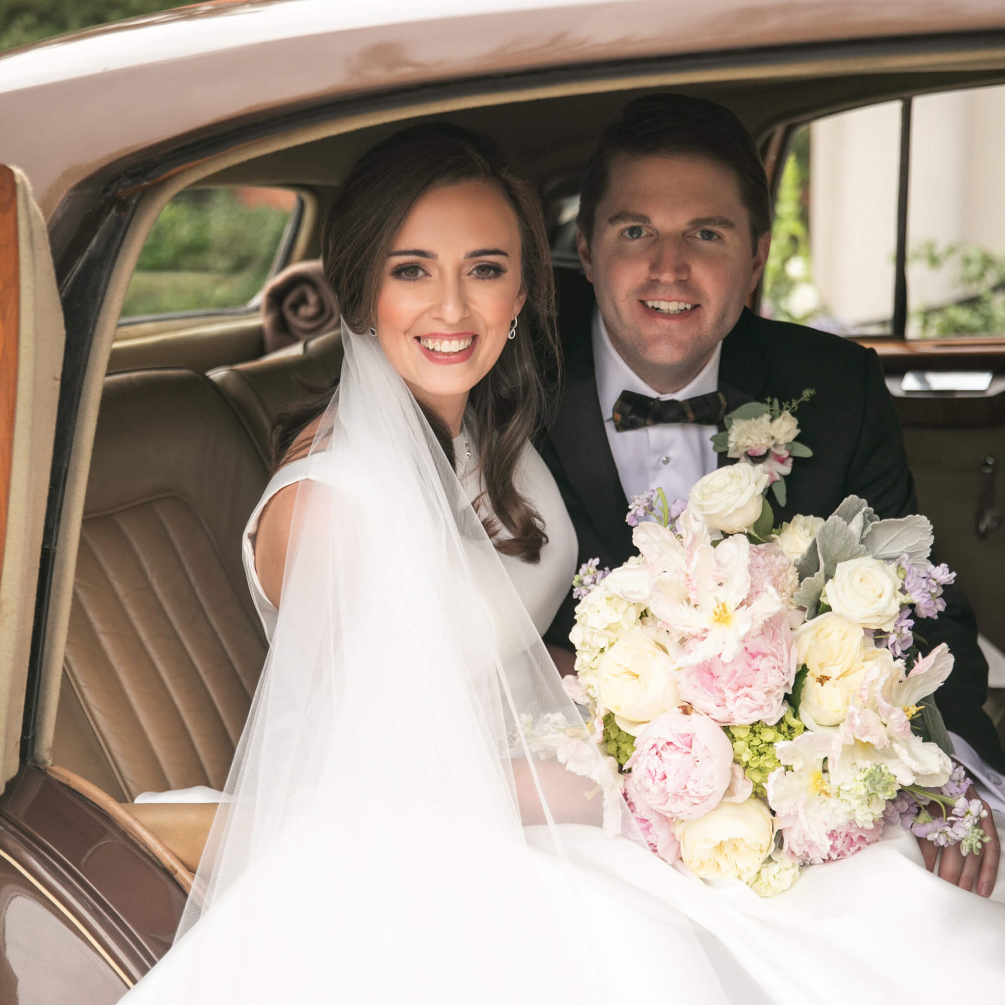 Bride and groom posing in car after ceremony